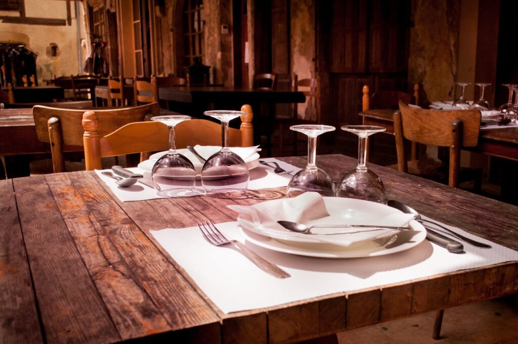menu-restaurant-france-eating-9315 A rustic restaurant table set with wine glasses and cutlery invites guests to dine.
