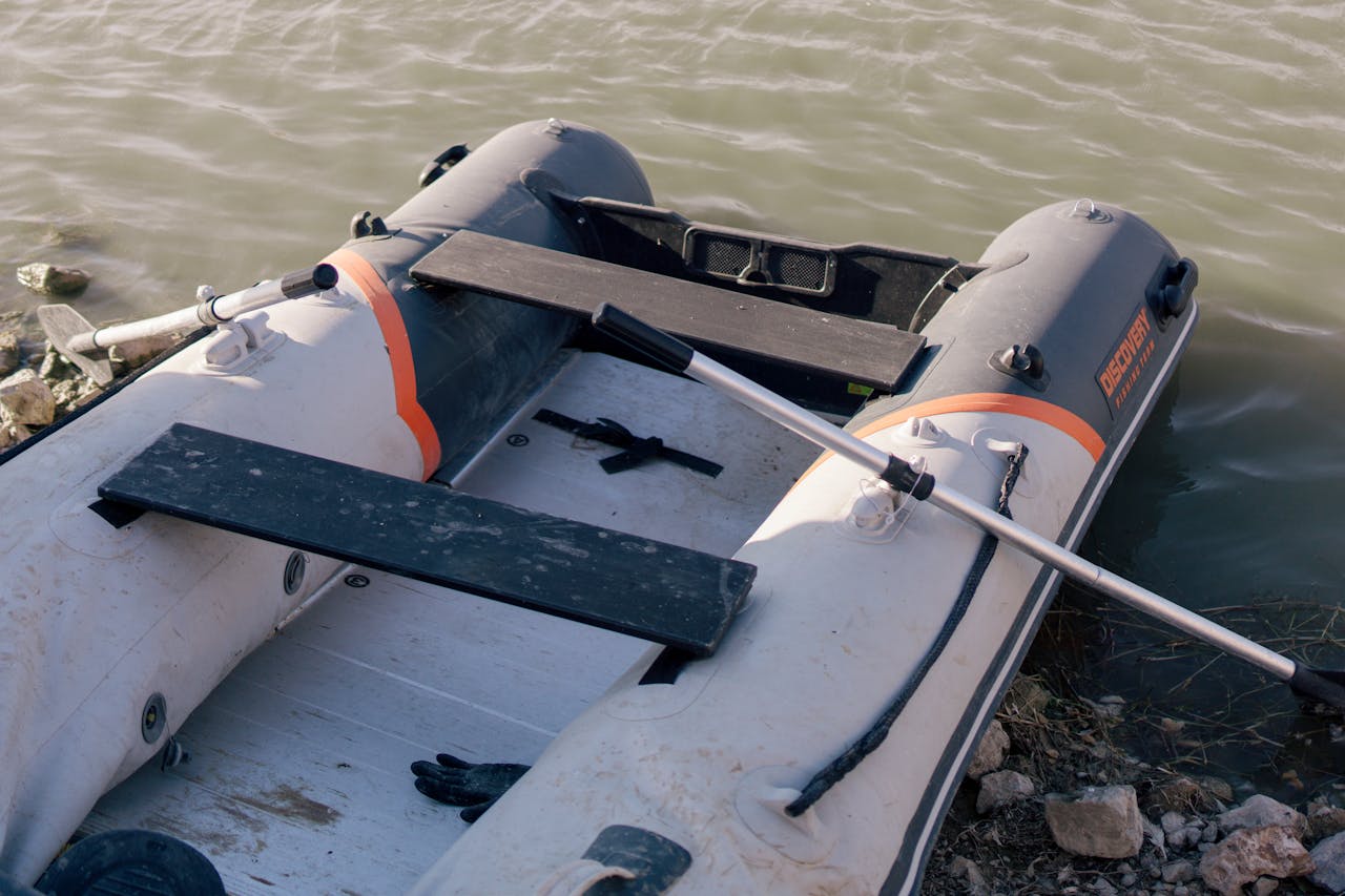 heros-img An inflatable boat with a paddle rests by the lakeside, ready for adventure.